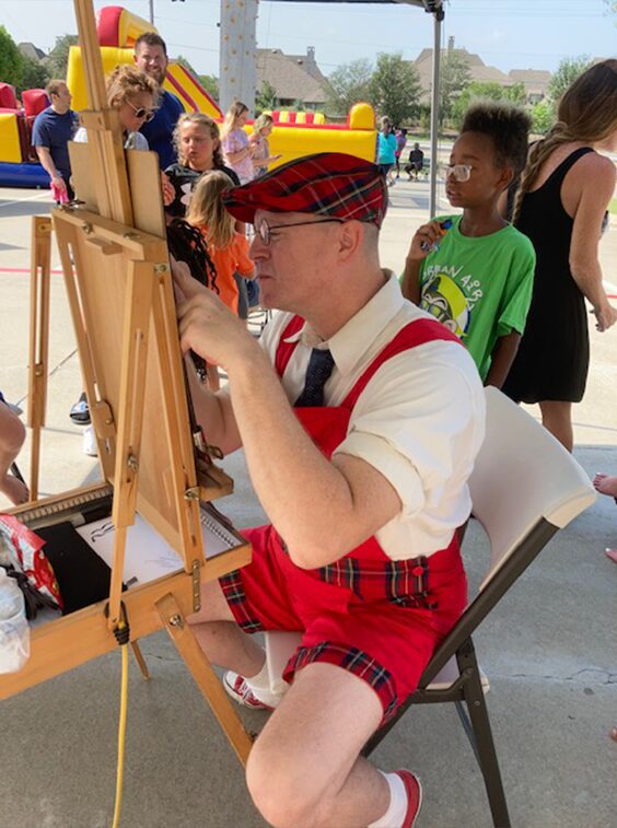 Artist drawing at outdoor event with children.
