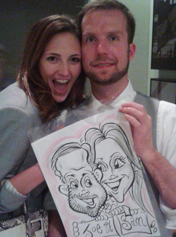 Couple smiling with a caricature drawing.