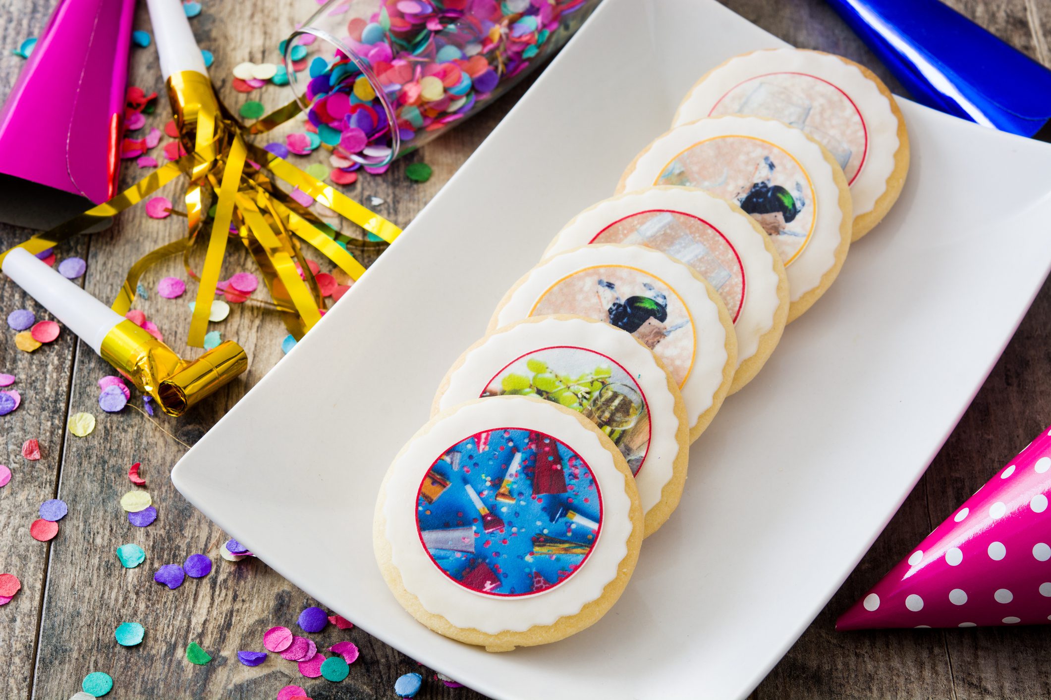 Decorated sugar cookies with colorful airplane designs on a white plate.