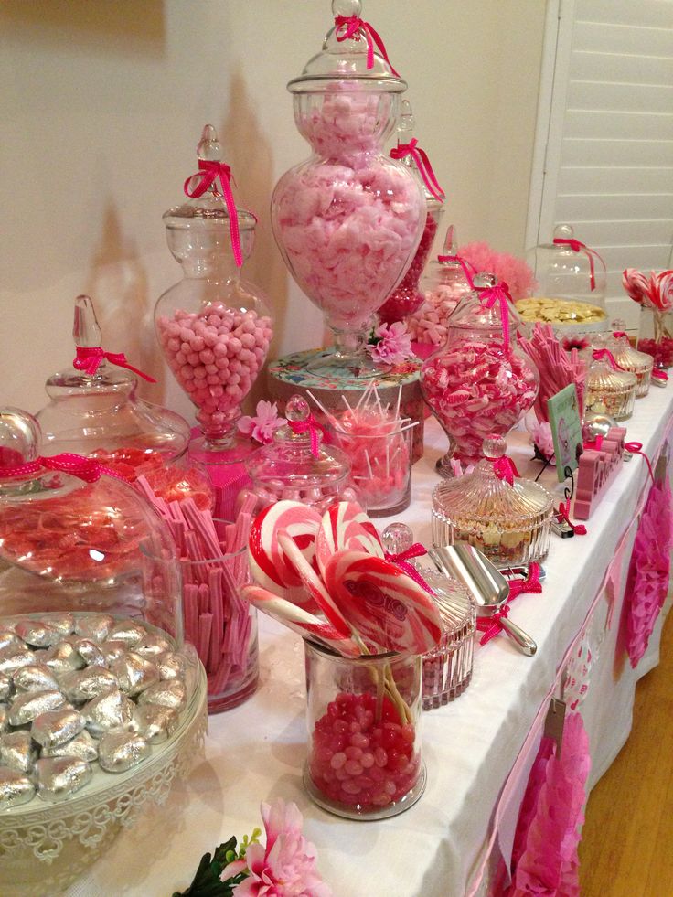 A festive pink-themed candy buffet with various sweets and candy canes.