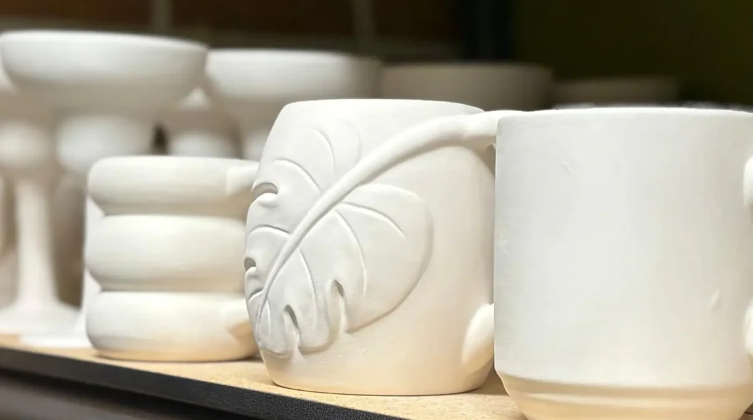 White ceramic cup with a leaf design on the side.