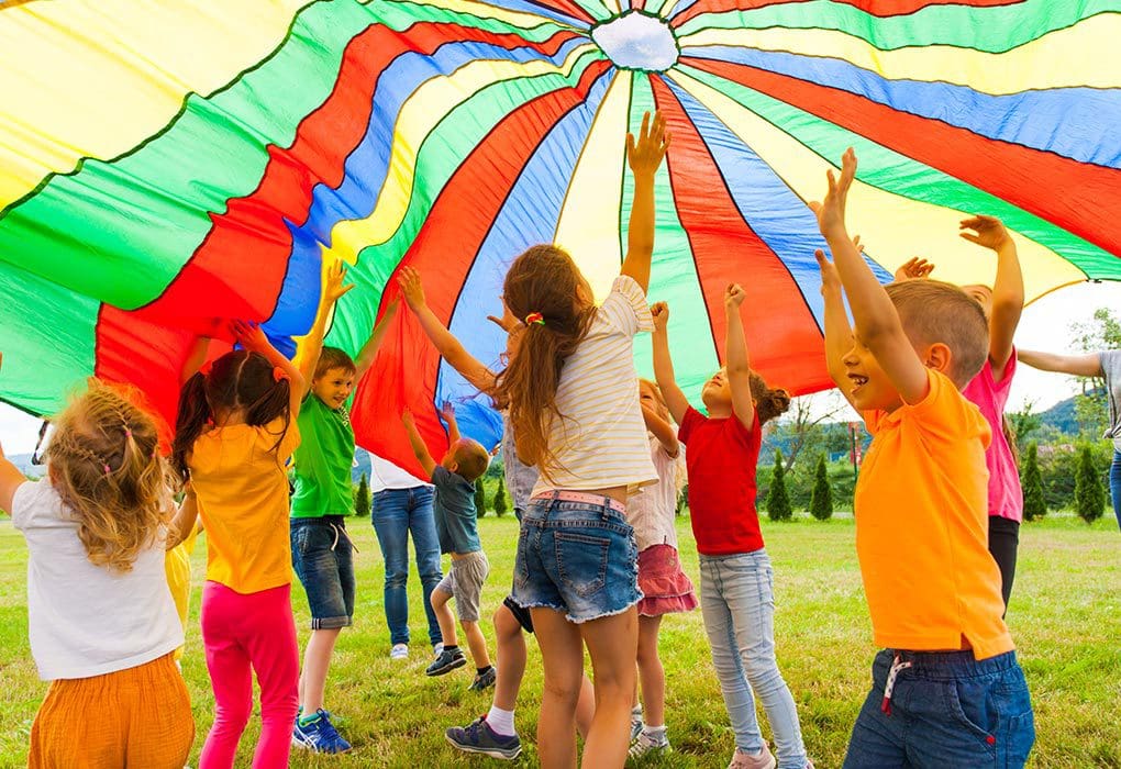 Children playing under a colorful parachute outdoors