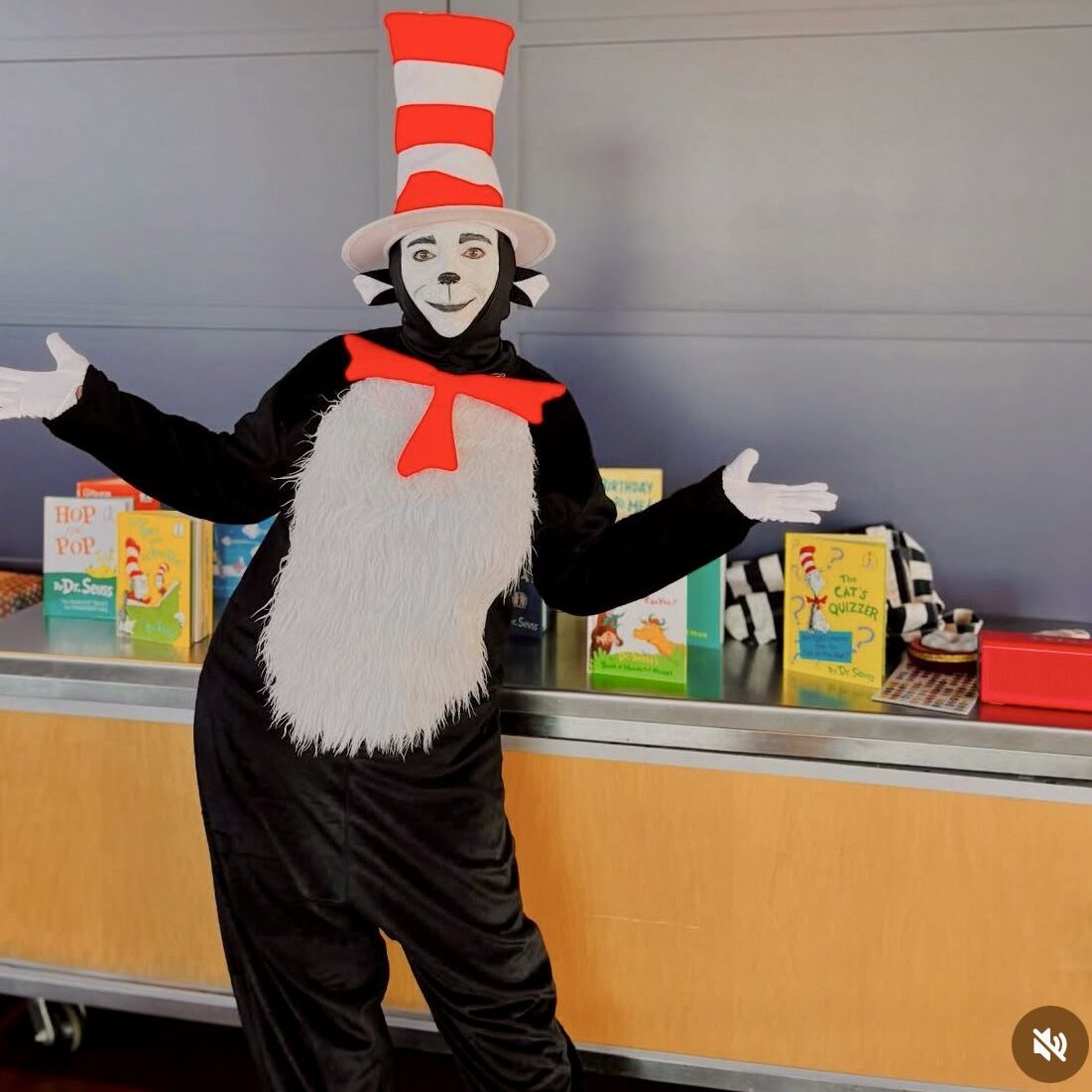 Person dressed as Cat in the Hat with books behind.
