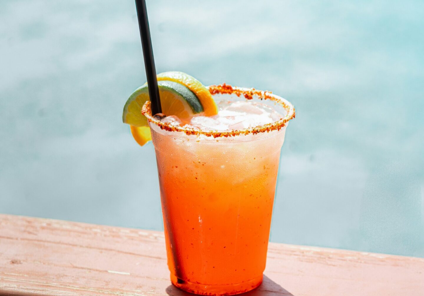 Orange cocktail with lime wedge by water