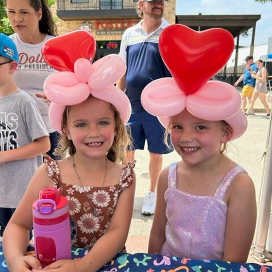 Two girls wearing heart-shaped balloon hats.