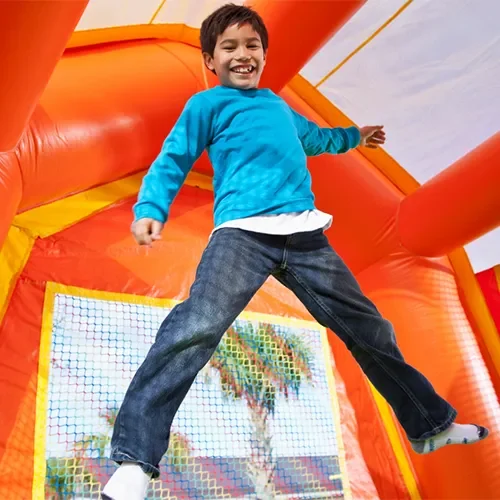 Child jumping in colorful bounce house.