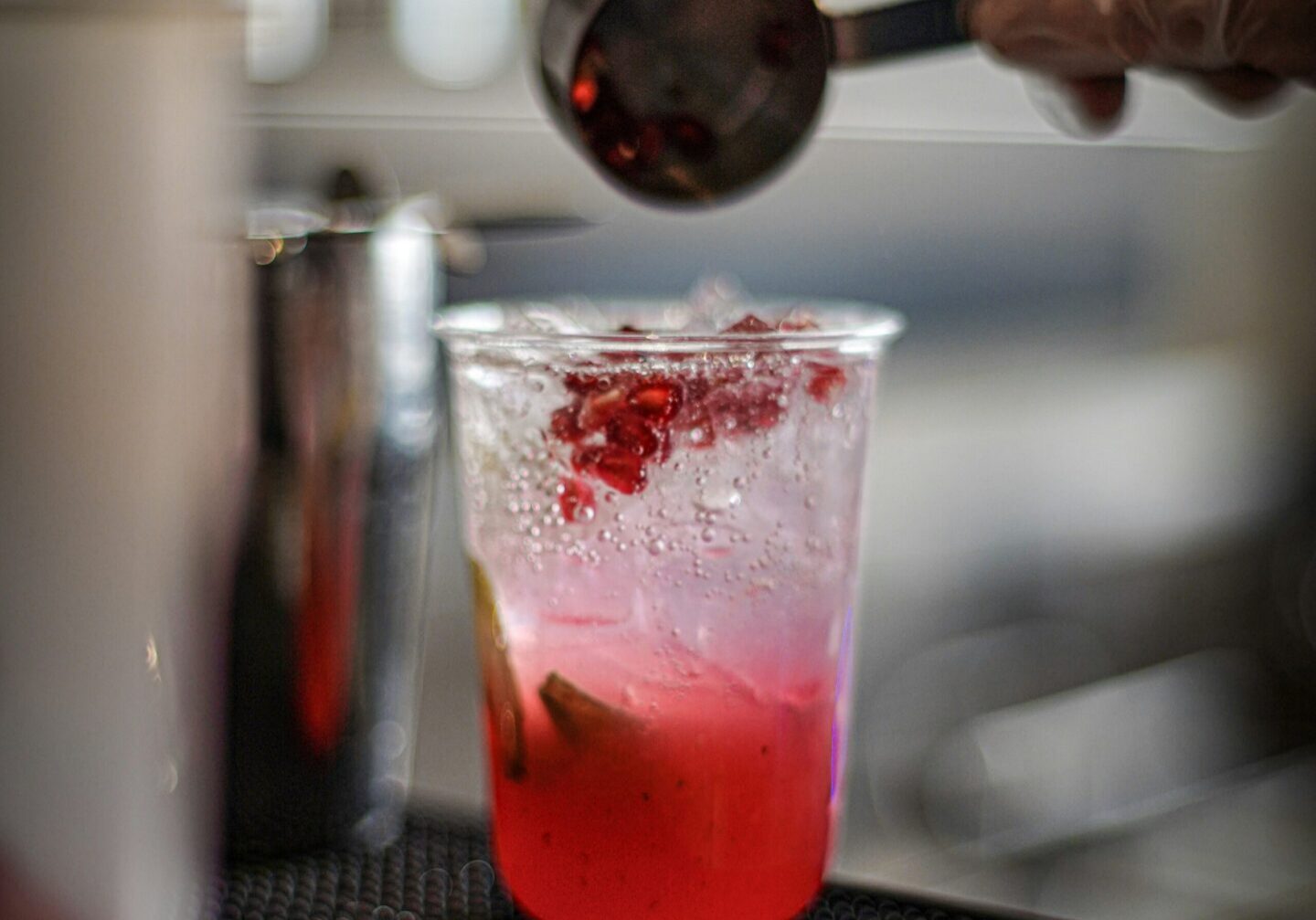 Hand spooning fruit into pink cocktail